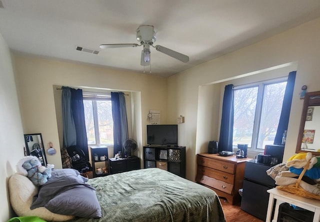 bedroom with ceiling fan, dark wood-type flooring, and multiple windows