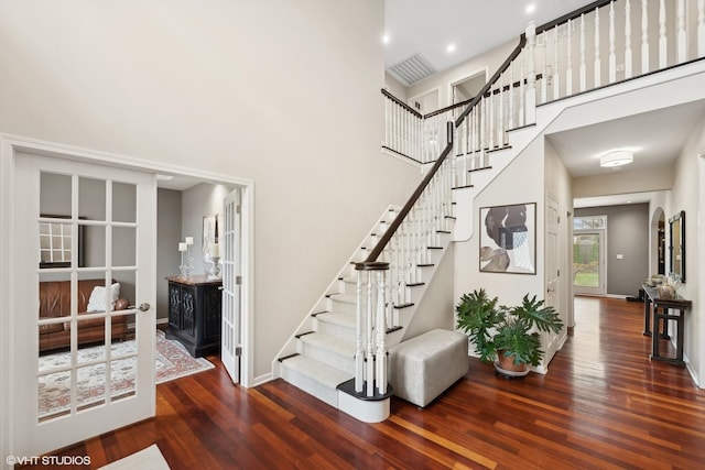 staircase with a towering ceiling and hardwood / wood-style floors