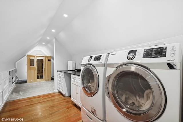 clothes washing area featuring light hardwood / wood-style flooring, washing machine and dryer, and cabinets