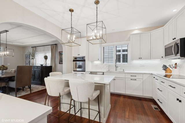 kitchen with white cabinetry, stainless steel appliances, sink, and pendant lighting