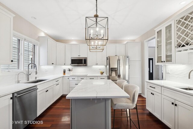 kitchen with stainless steel appliances, white cabinetry, a center island, and sink