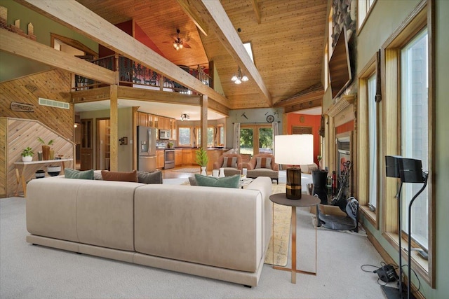 living area with light colored carpet, wood walls, visible vents, wood ceiling, and beamed ceiling