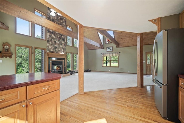 kitchen featuring high vaulted ceiling, light wood-style flooring, open floor plan, freestanding refrigerator, and dark countertops