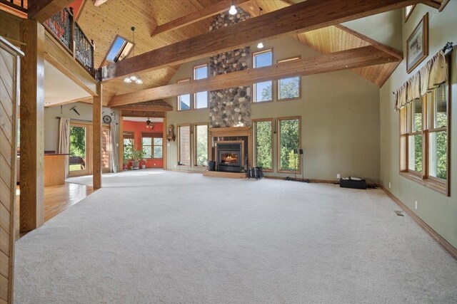 unfurnished living room with carpet, wooden ceiling, beamed ceiling, and a stone fireplace