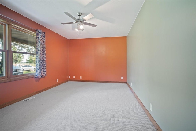 spare room featuring baseboards, a ceiling fan, visible vents, and light colored carpet