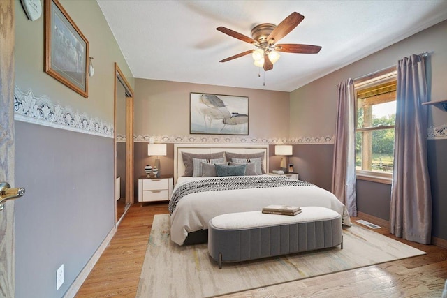 bedroom featuring a ceiling fan, baseboards, visible vents, and wood finished floors