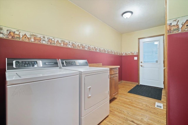 clothes washing area featuring cabinet space, baseboards, visible vents, washer and clothes dryer, and light wood-style floors