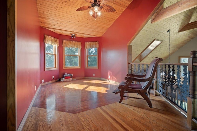 unfurnished room with ceiling fan, wooden ceiling, a skylight, wood finished floors, and baseboards