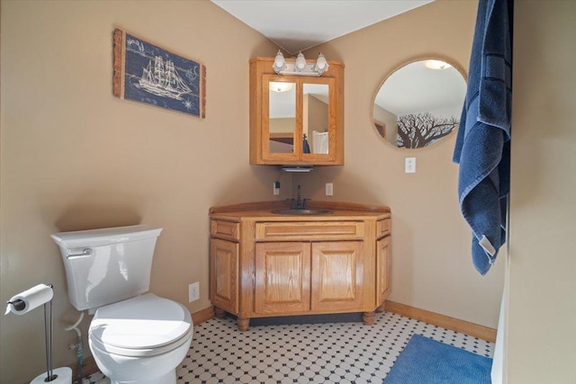 half bathroom with vanity, toilet, and baseboards