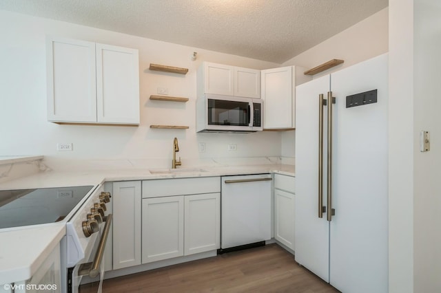 kitchen with white appliances, sink, light hardwood / wood-style flooring, a textured ceiling, and white cabinetry