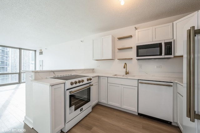 kitchen featuring white cabinetry, dishwasher, sink, electric range oven, and kitchen peninsula