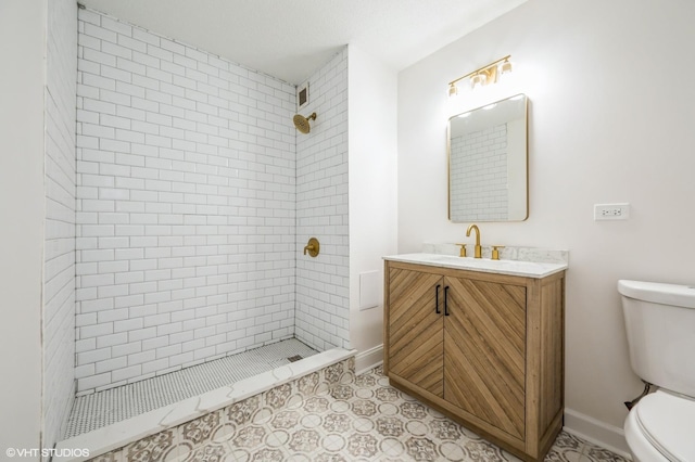 bathroom featuring tiled shower, vanity, and toilet