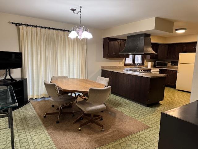 kitchen with pendant lighting, exhaust hood, dark brown cabinetry, and stainless steel appliances