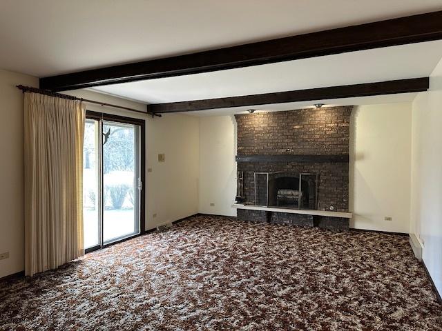 unfurnished living room featuring beam ceiling, a fireplace, and carpet floors