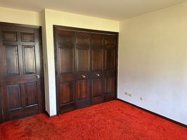 unfurnished bedroom featuring dark carpet and a closet