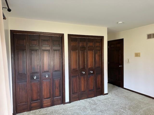 unfurnished bedroom with light carpet and multiple closets