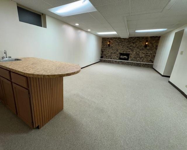 basement with light colored carpet, sink, brick wall, and a brick fireplace