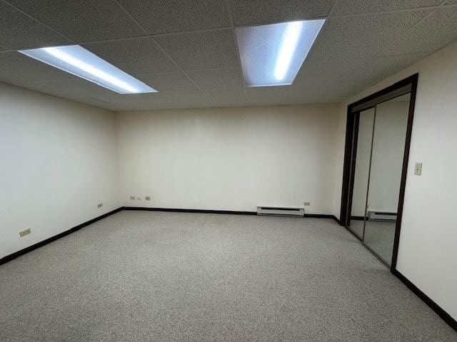 unfurnished room with a paneled ceiling, carpet floors, and a baseboard heating unit