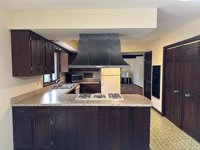 kitchen featuring sink, kitchen peninsula, dark brown cabinetry, stainless steel appliances, and extractor fan