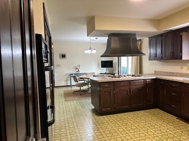 kitchen with kitchen peninsula, custom exhaust hood, decorative light fixtures, an inviting chandelier, and stainless steel gas stovetop