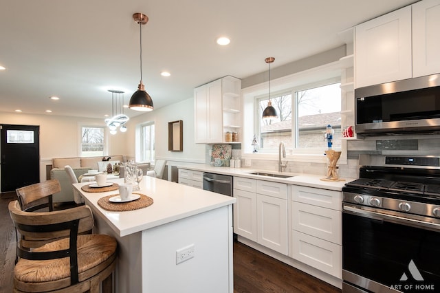 kitchen with appliances with stainless steel finishes, a center island, white cabinetry, and sink