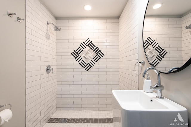 bathroom featuring tiled shower and sink