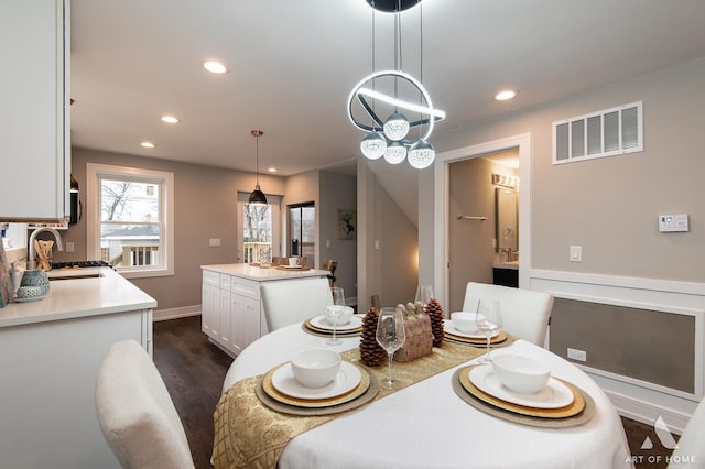 dining area with dark hardwood / wood-style flooring, sink, and an inviting chandelier