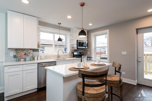 kitchen featuring appliances with stainless steel finishes, white cabinetry, hanging light fixtures, and sink