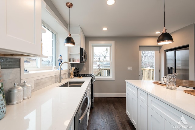 kitchen featuring white cabinetry, sink, dark wood-type flooring, decorative light fixtures, and appliances with stainless steel finishes