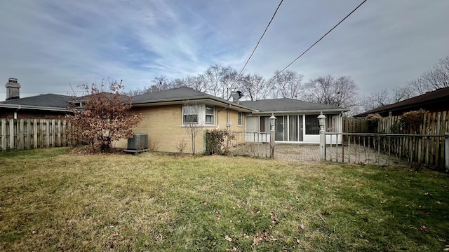 rear view of property featuring a lawn, central AC, and a sunroom