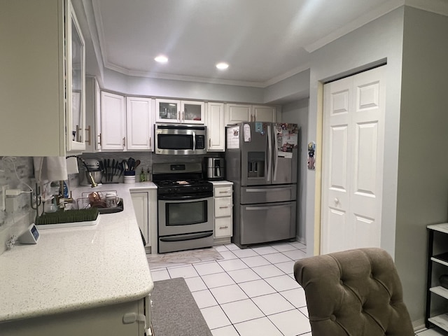 kitchen with crown molding, appliances with stainless steel finishes, light tile patterned floors, and white cabinets