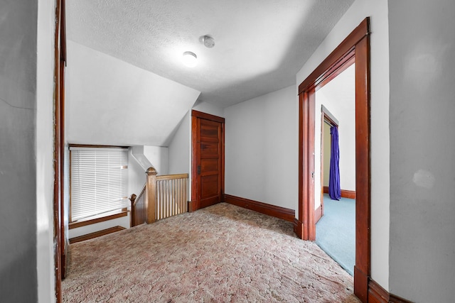 bonus room with light carpet, vaulted ceiling, and a textured ceiling