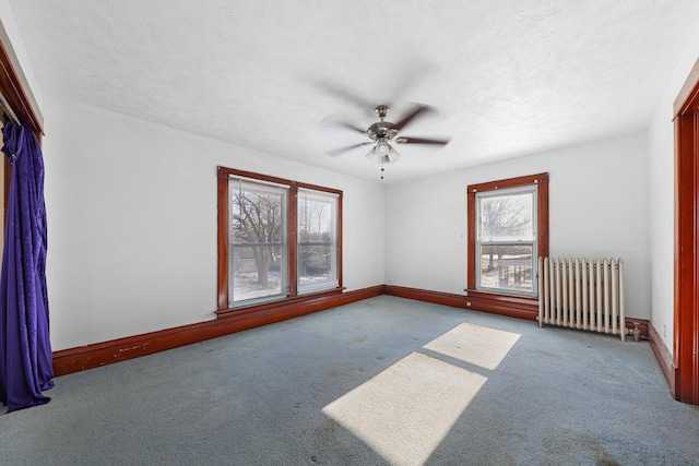 empty room featuring radiator, a textured ceiling, light colored carpet, and ceiling fan