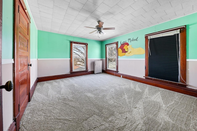 empty room featuring carpet flooring, radiator heating unit, and ceiling fan