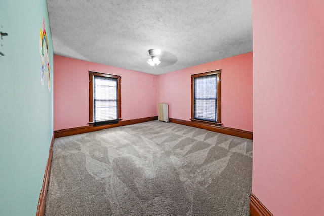 carpeted empty room with radiator and a textured ceiling