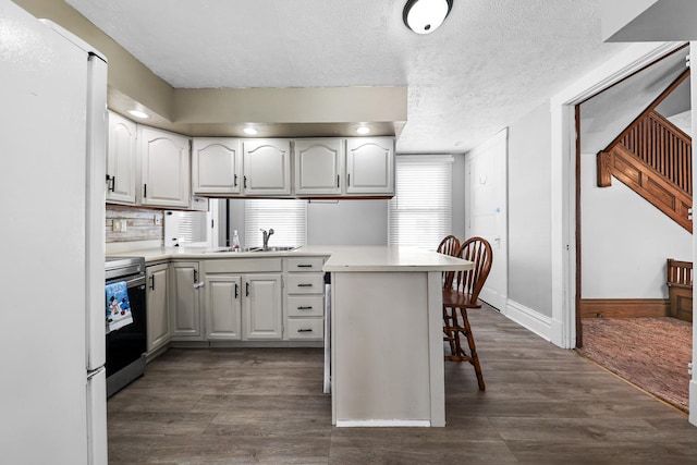 kitchen featuring sink, white refrigerator, kitchen peninsula, stainless steel electric stove, and white cabinets