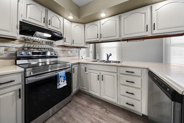 kitchen with appliances with stainless steel finishes, white cabinetry, tasteful backsplash, dark hardwood / wood-style flooring, and kitchen peninsula