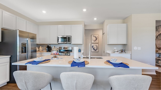 kitchen with a kitchen island with sink, dark hardwood / wood-style flooring, white cabinets, and appliances with stainless steel finishes