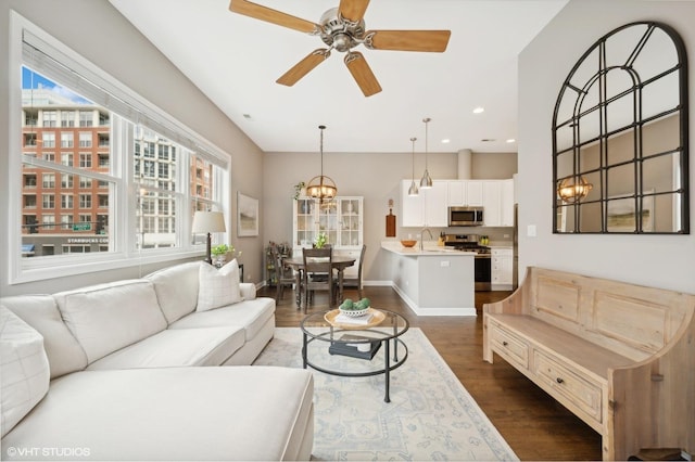 living room featuring dark hardwood / wood-style floors, sink, and ceiling fan with notable chandelier