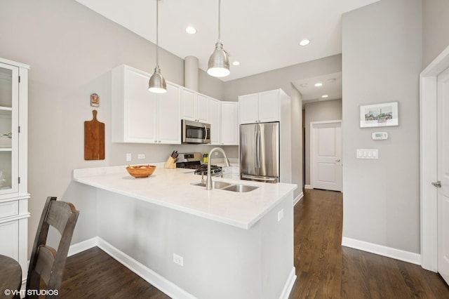 kitchen featuring sink, hanging light fixtures, kitchen peninsula, white cabinets, and appliances with stainless steel finishes