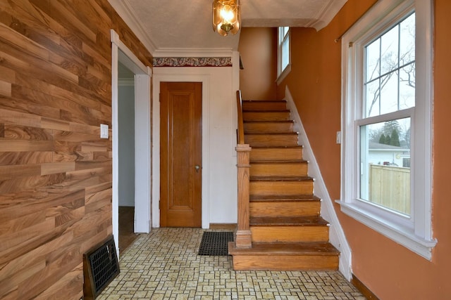 stairs featuring wooden walls and ornamental molding