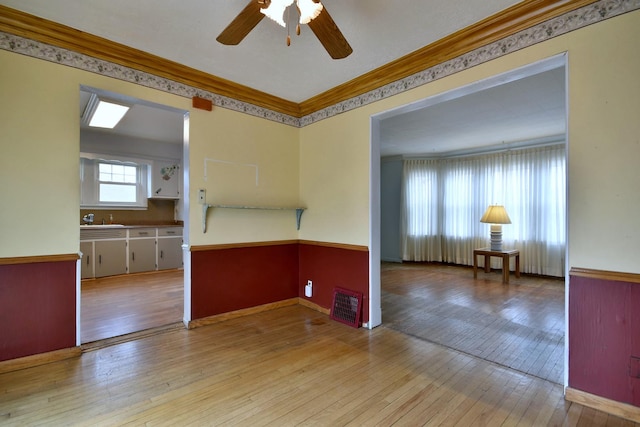 spare room featuring ornamental molding, sink, ceiling fan, and light wood-type flooring