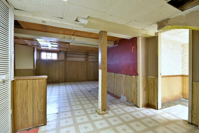 basement with a paneled ceiling and wooden walls