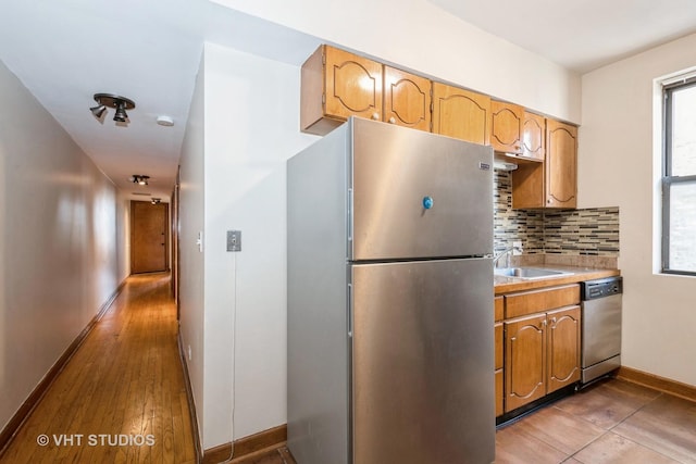 kitchen with decorative backsplash, sink, light hardwood / wood-style flooring, and appliances with stainless steel finishes