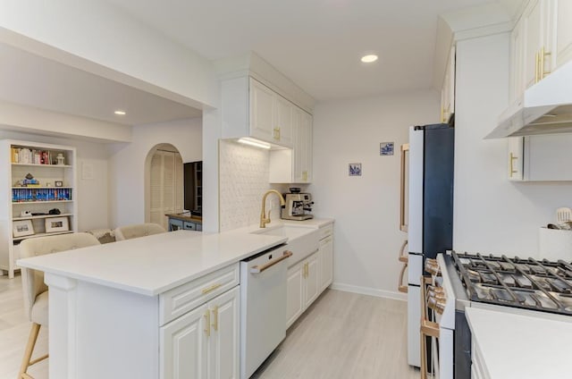 kitchen with a breakfast bar area, kitchen peninsula, white cabinets, and white appliances