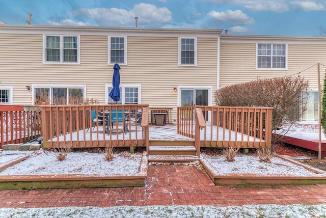 snow covered house featuring a wooden deck