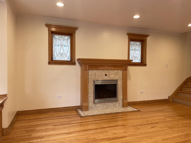 unfurnished living room featuring a tile fireplace, light wood-type flooring, and crown molding