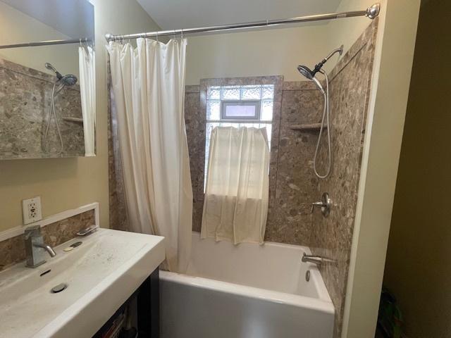 bathroom with shower / bath combo with shower curtain and sink