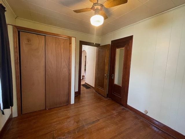 unfurnished bedroom with ceiling fan, dark wood-type flooring, and a closet