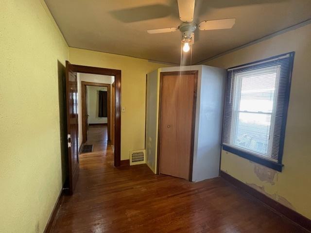 unfurnished bedroom with dark hardwood / wood-style flooring, a closet, and ceiling fan